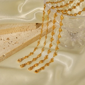 Detail of four 18k gold plated stainless steel heart and shell chain necklaces on silk