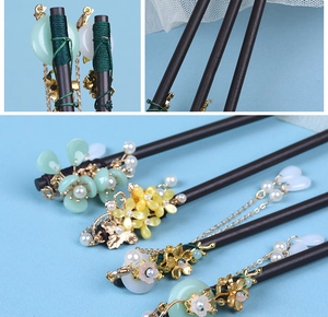 Detail of wooden hair sticks with gold metal accents, green beads and tassels in retro style