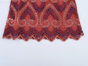 Dettaglio del top rosso con ricamo floreale colorato e bordo smerlato con occhielli