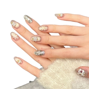 Handmade champagne press-on nails with glitter, pearls, and gold foil flower patterns