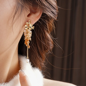 Close-up of golden flower earrings with sparkling crystals and gradient beaded tassels