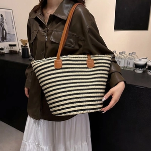 Large black and white striped woven straw tote bag with brown leather shoulder straps