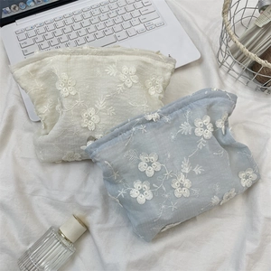 Close-up of floral embroidery on soft cream and blue pouch with a zipper closure