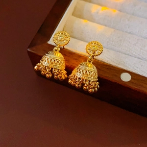 Macro detail of golden Indian style Jhumka earrings with intricate hollow engravings