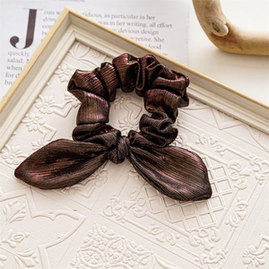 Detail of dark red metallic fabric hair scrunchie with bow on vintage paper background