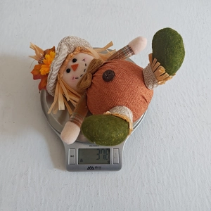 Close-up of lightweight harvest scarecrow doll weighing 37.8g on a digital scale