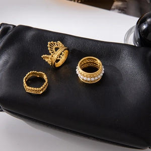 Detailed view of three gold vintage lace rings with white pearls on a black leather surface