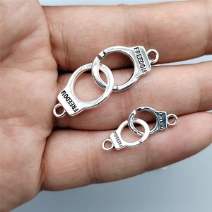 Silver handcuff-shaped alloy charms engraved with FREEDOM held in a hand palm