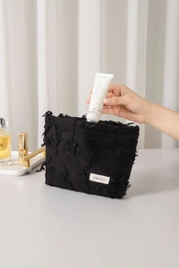 Close-up of black fringed linen cosmetic bag showing large storage capacity and texture