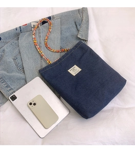 Détail du sac cabas en jean bleu avec poignée en perles et comparaison de taille iPad