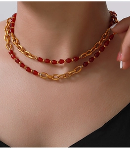 Close-up of elegant double-layered gold titanium necklace with red agate beads on a model