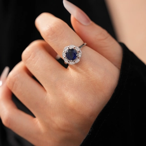 Close-up of a hollow diamond-shaped ring with a large blue zircon and floral crystals