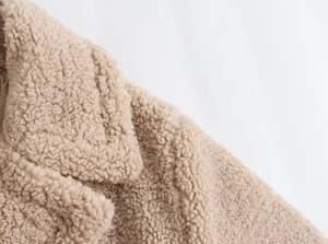 Gros plan détaillé du col d'une veste en polaire beige montrant la texture douce du tissu