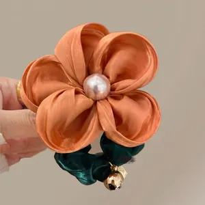 Detailed close-up of handmade floral hair scrunchie with orange satin flower and pearl