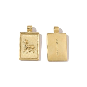 Detail view of 18k gold Aries zodiac pendant showing embossed ram and engraved text