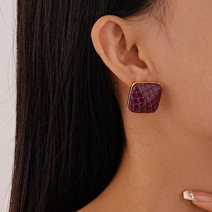 Close-up of square purple snakeskin pattern earrings with gold metallic frame edges