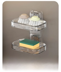 Dual-layer clear wall-mounted rack showing kitchen brush and sponge storage detail