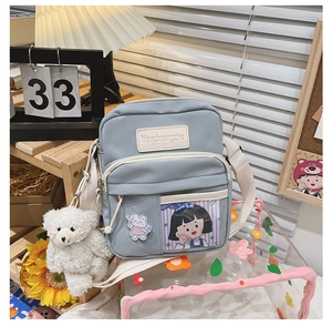 Détail du sac bandoulière en toile bleu clair avec fente PVC et ours en peluche blanc