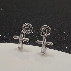 Detailed macro view of silver cross earrings with step-cut crystals and screw-back clips