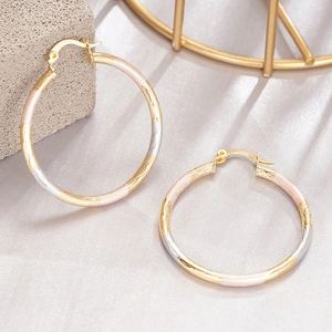 Detailed view of tricolor wave texture hoop earrings on luxury silk background