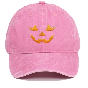 Close-up of orange pumpkin face embroidery on a pink washed cotton baseball cap