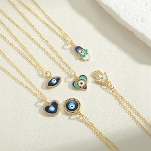 Detail of Hamsa Hand and Evil Eye gold pendants with colorful enamel on white stone