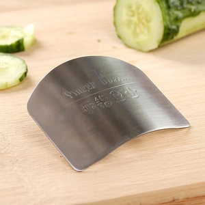 Stainless steel finger guard for cutting vegetables on a wooden board with cucumber slices