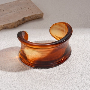 Detailed view of amber acrylic open bangle showing translucent resin texture and light