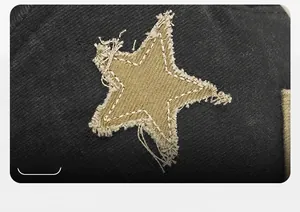 Macro detail of khaki star patch with frayed edges on black twill docker hat