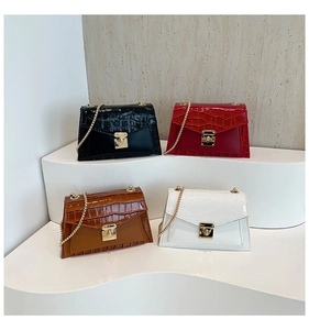 Detail of four faux crocodile leather bags in black, red, brown, and white with gold chains