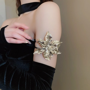 Detailed view of an oversized silver metal flower arm cuff with liquid metal texture on model