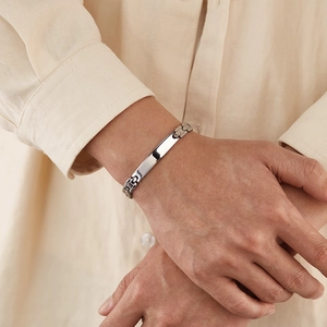 Close-up of a minimalist silver stainless steel curved bar bracelet on a male wrist