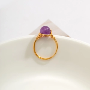 Detailed macro shot of handmade gold wire-wrapped ring with a purple amethyst bead