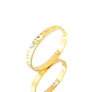 Polished gold heart cutout bangle with cubic zirconia accents on a reflective surface