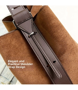 Close-up of adjustable leather strap and metal buckle on brown suede tote bag