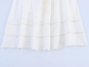 Close-up of white skirt hem featuring delicate floral embroidery and lace trim details