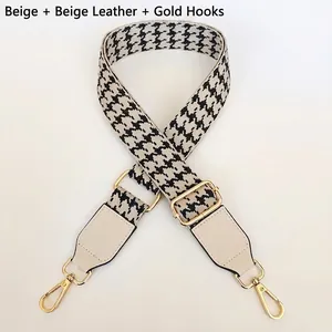 Detail of adjustable houndstooth bag strap with cream leather and gold metal hooks