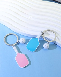 Detail shot of pickleball paddle keychain with miniature white ball on wave display stand
