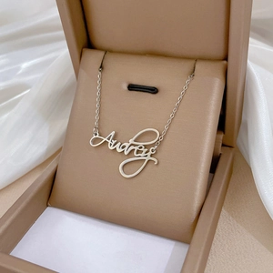 Customized Audrey name necklace in silver-tone titanium steel on a jewelry box