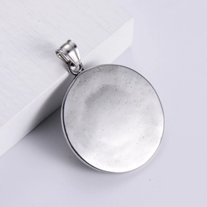 Silver round lion head stainless steel pendant displayed on a minimalist white block