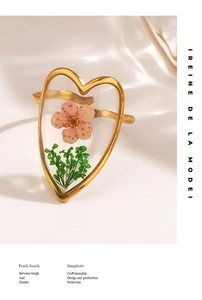 Detail of a golden heart ring featuring real preserved pink flowers and green leaves