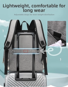 Detail of the gray diaper bag showing its back trolley strap attached to a silver suitcase