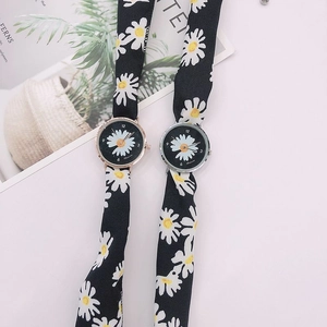 Detail of daisy patterned ribbon straps on fashionable watches in silver and rose gold
