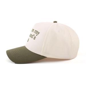 Detailed embroidery on the side of a two-tone beige and olive cotton baseball cap