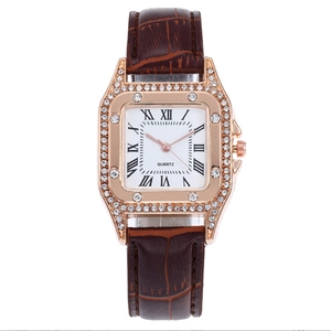 Detail of rose gold square watch case with crystal bezel and brown leather strap