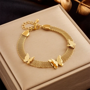 Macro detail of gold-toned mesh chain bracelet featuring frosted butterfly pendants