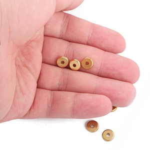Golden stainless steel wheel spacer beads for jewelry making held in a palm