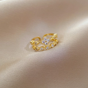 Macro view of gold-plated clover ring with white zircon stones on champagne silk