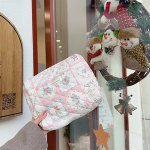 Détail de la trousse cosmétique matelassée fleurie avec motifs nœuds et étiquette