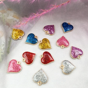 Vue détaillée de pendentifs cœurs pailletés colorés pour bijoux DIY sur fond de maille